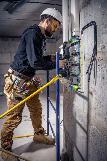 male-electrician-works-switchboard-with-electrical-connecting-cable